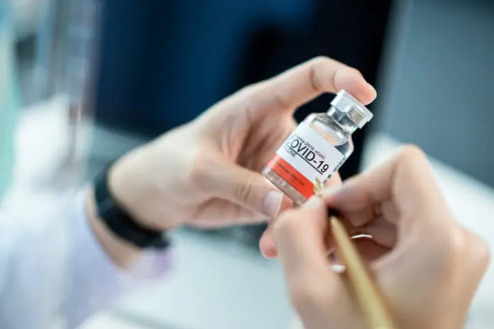 Doctor writing a note on COVID-19 vaccine